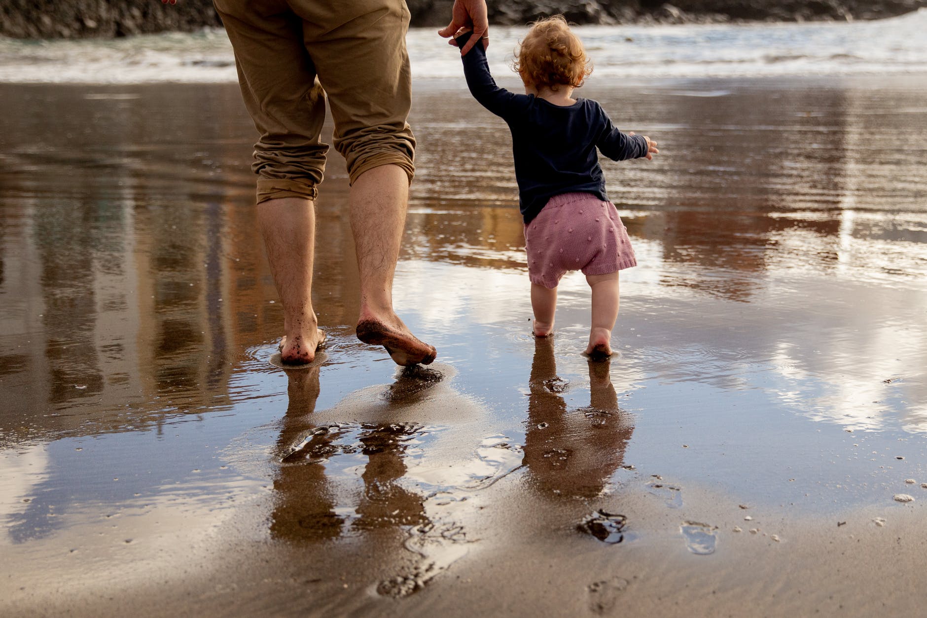 father and child walking on the shore